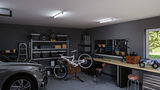 Garage moderne avec voiture grise, vélo sur support de réparation, établi organisé et éclairage LED au plafond