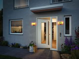 Modern house entrance with white door, illuminated house number sign, and warm outdoor wall light.