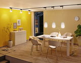 Moderne eetkamer met witte stoelen, houten vloer en drie witte hanglampen aan zwarte rails