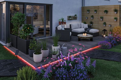 Modern garden with grey lounge set, wooden deck and red LED lighting for outdoor ambiance.