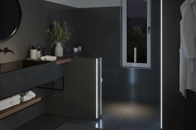 Modern bathroom with dark tiles and LED light strips providing ambient lighting effect