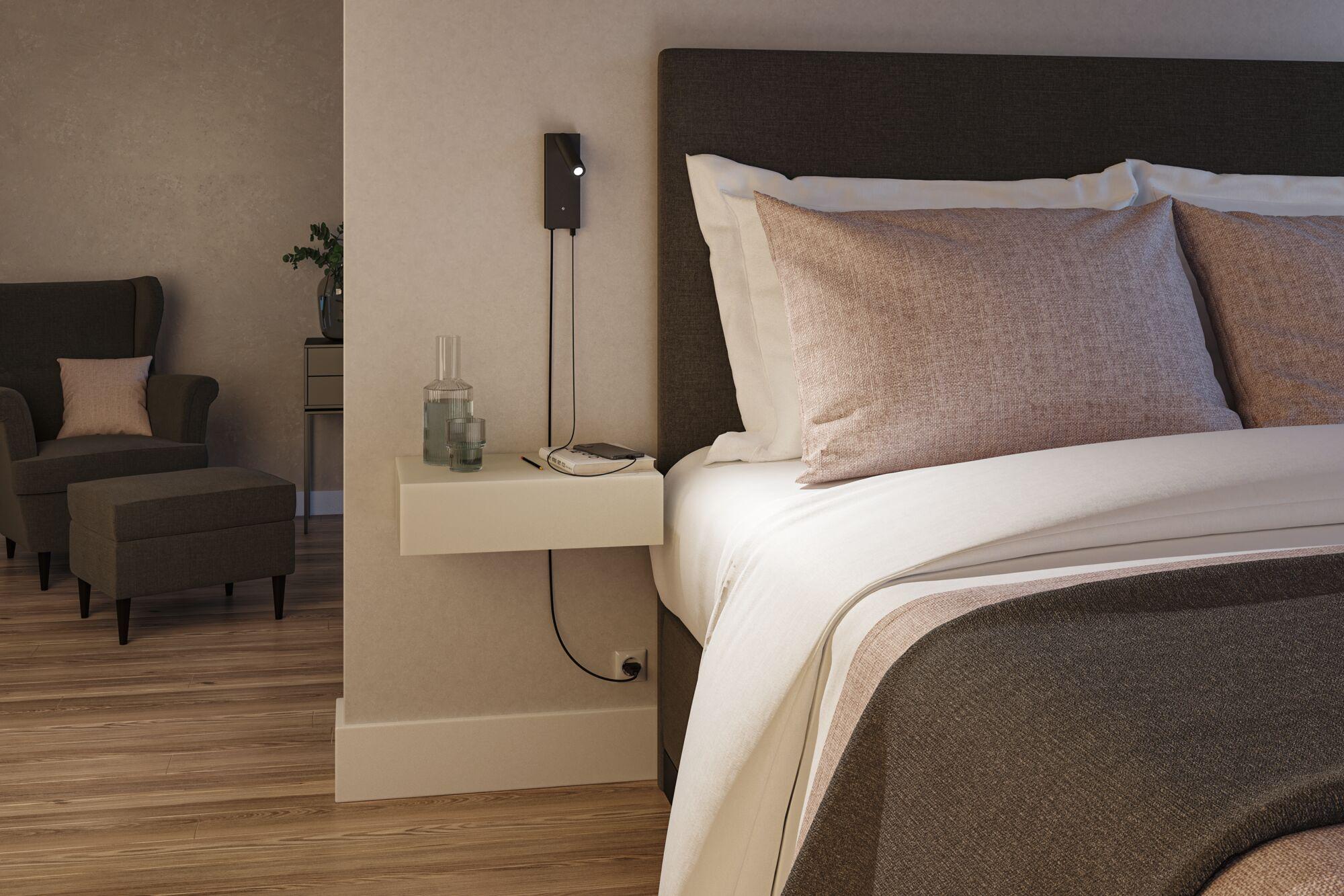 Modern bedroom with brown fabric bed, beige wall lamp, and floating wooden bedside table.