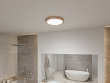 Round ceiling light with wooden frame in modern bathroom featuring bathtub and shower.