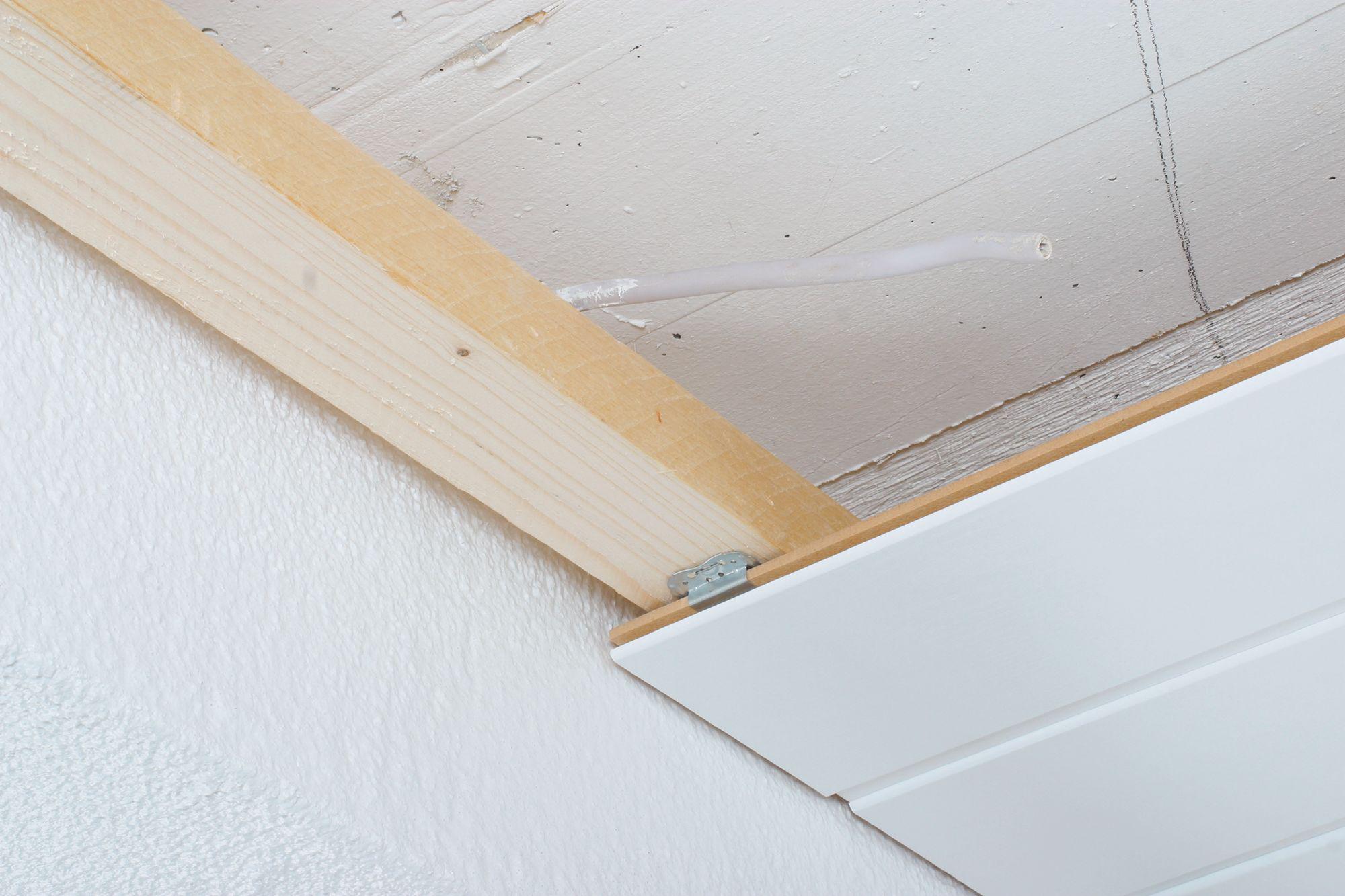 White wooden ceiling panels with visible mounting and cable for modern room lighting installation