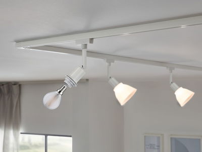 Système d'éclairage sur rail LED blanc avec trois spots réglables dans un salon moderne éclairé par la lumière du jour.