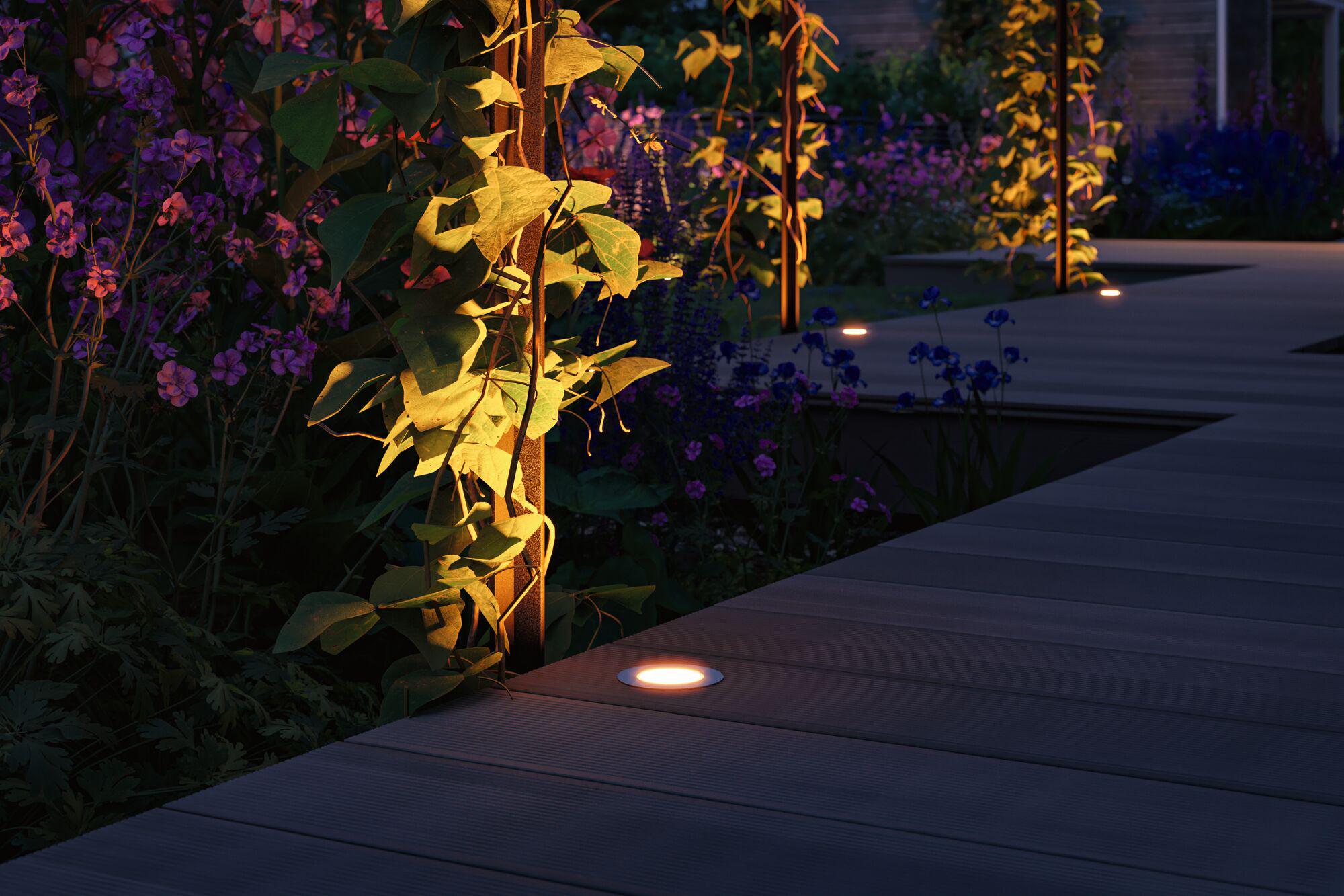 Warm white LED recessed floor lights on wooden terrace with garden path and plant illumination.