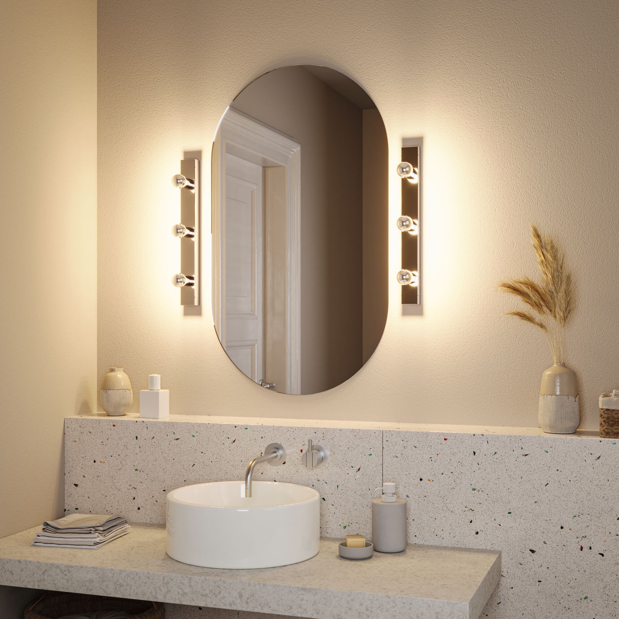 Modern bathroom with oval mirror and two warm white metal wall lights beside white sink and terrazzo countertop.