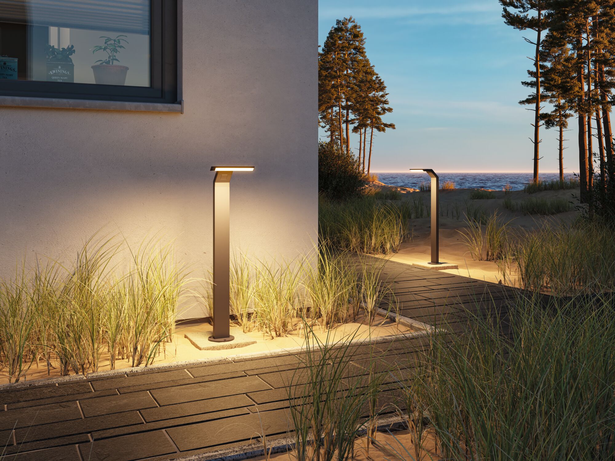 Modern anthracite metal LED path light illuminating garden walkway at dusk with sea view