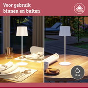 Witte tafellamp met IP44 bescherming voor binnen- en buitengebruik op houten tafel met servies.