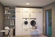 Moderne weiße Einbau-Waschküche mit Waschmaschine, Trockner und integriertem Wäschekorb in Schublade.
