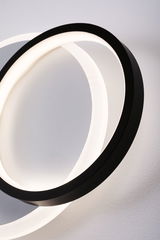Moderne LED-Wandleuchte mit zwei ineinander verschlungenen Ringen in Schwarz und warmweißem Licht