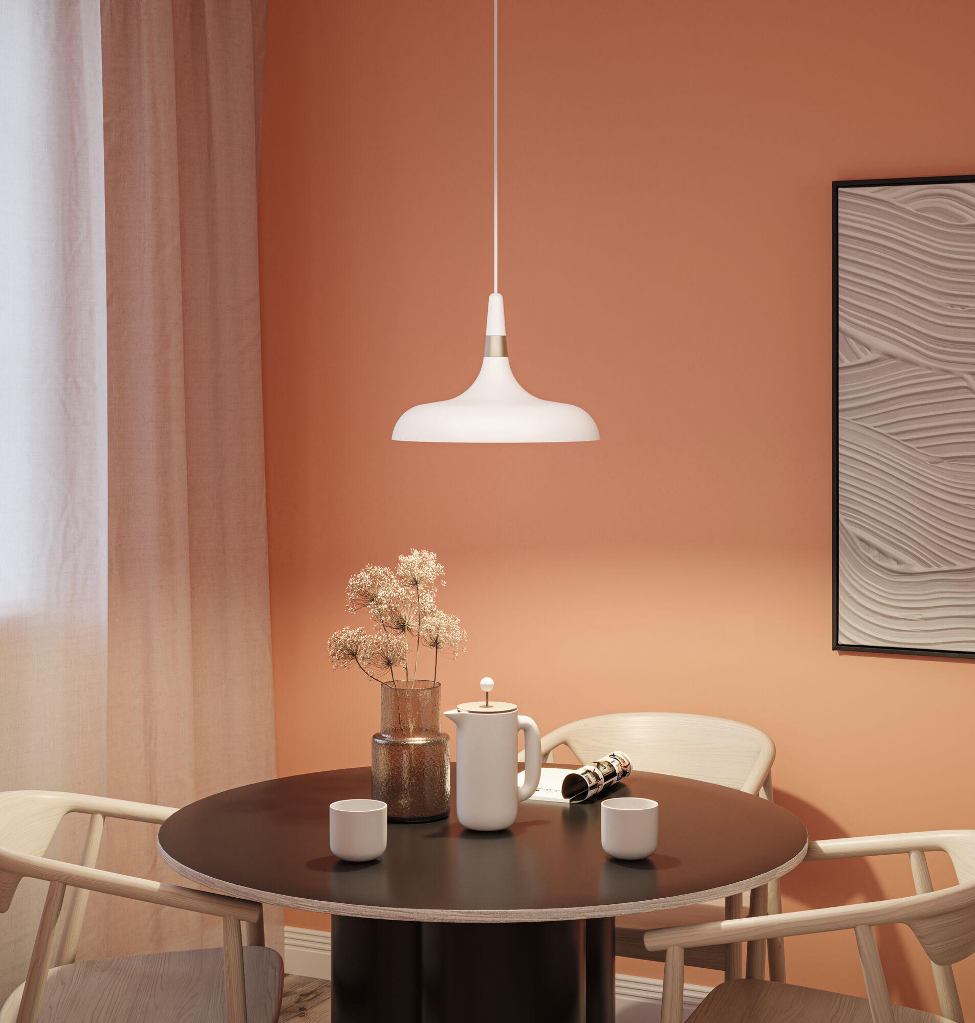 White metal pendant lamp against terracotta wall in modern dining room setting