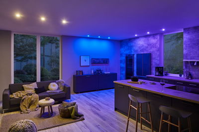 Living room with modern RGBW downlights in ceiling, blue and white LED lighting creating atmospheric mood lighting