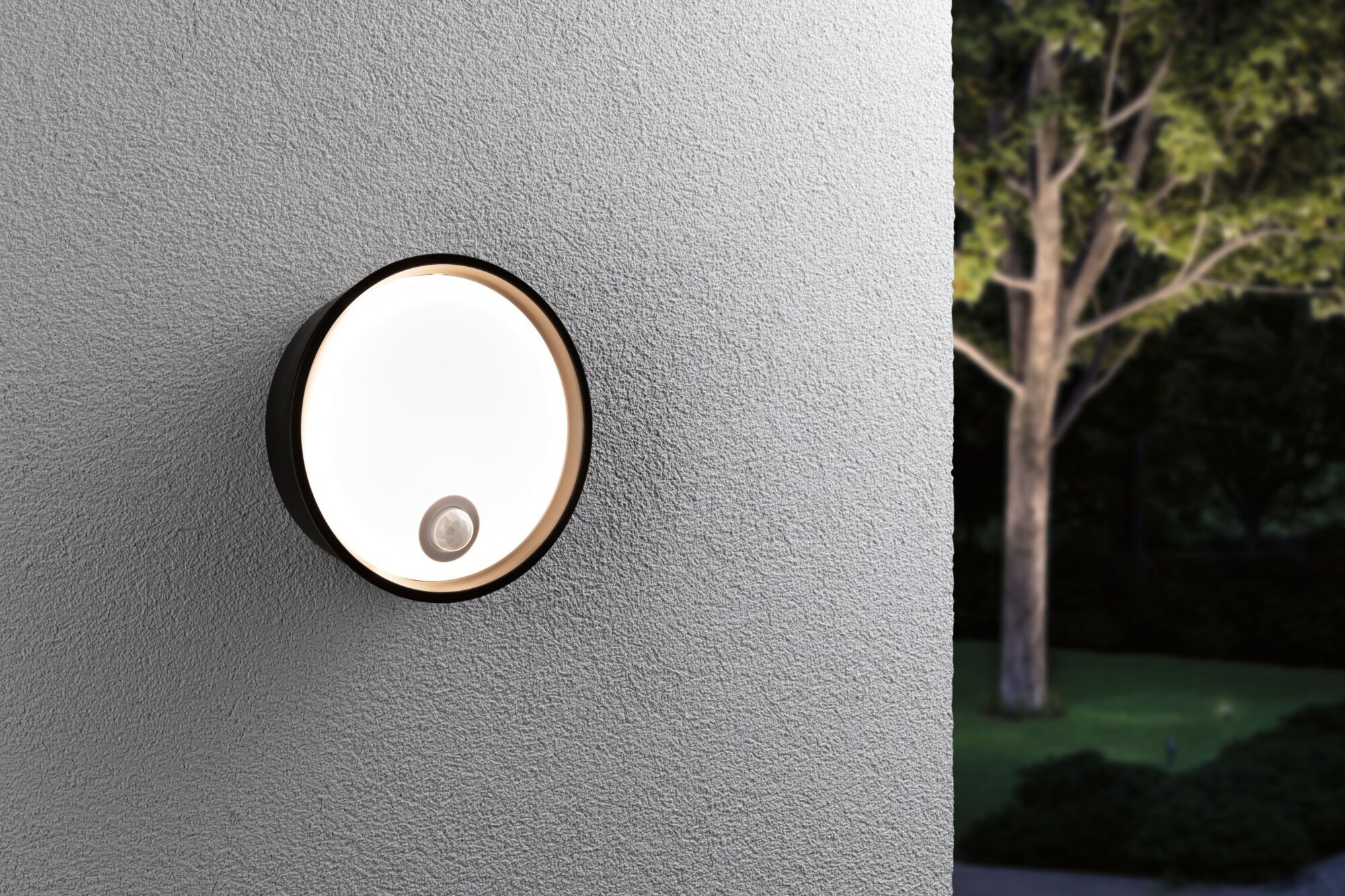 Runde schwarze Außenwandleuchte mit Bewegungsmelder an grauer Wand, moderne LED-Gartenbeleuchtung
