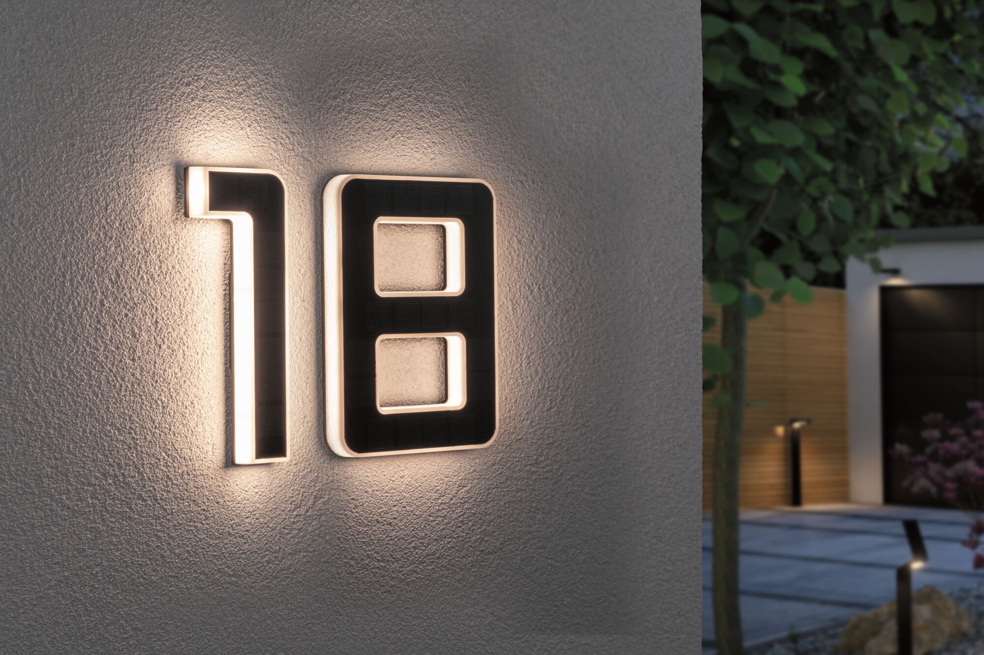 Modern house number 18 in black material with warm white LED lighting on exterior wall