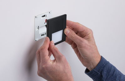 Hand montiert schwarzen LED-Wandeinbauleuchte mit weißem Diffusor an weiße Wand für Innenbeleuchtung