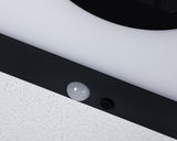 Gros plan sur cadre de lampe LED noir avec détecteur de mouvement blanc sur mur blanc