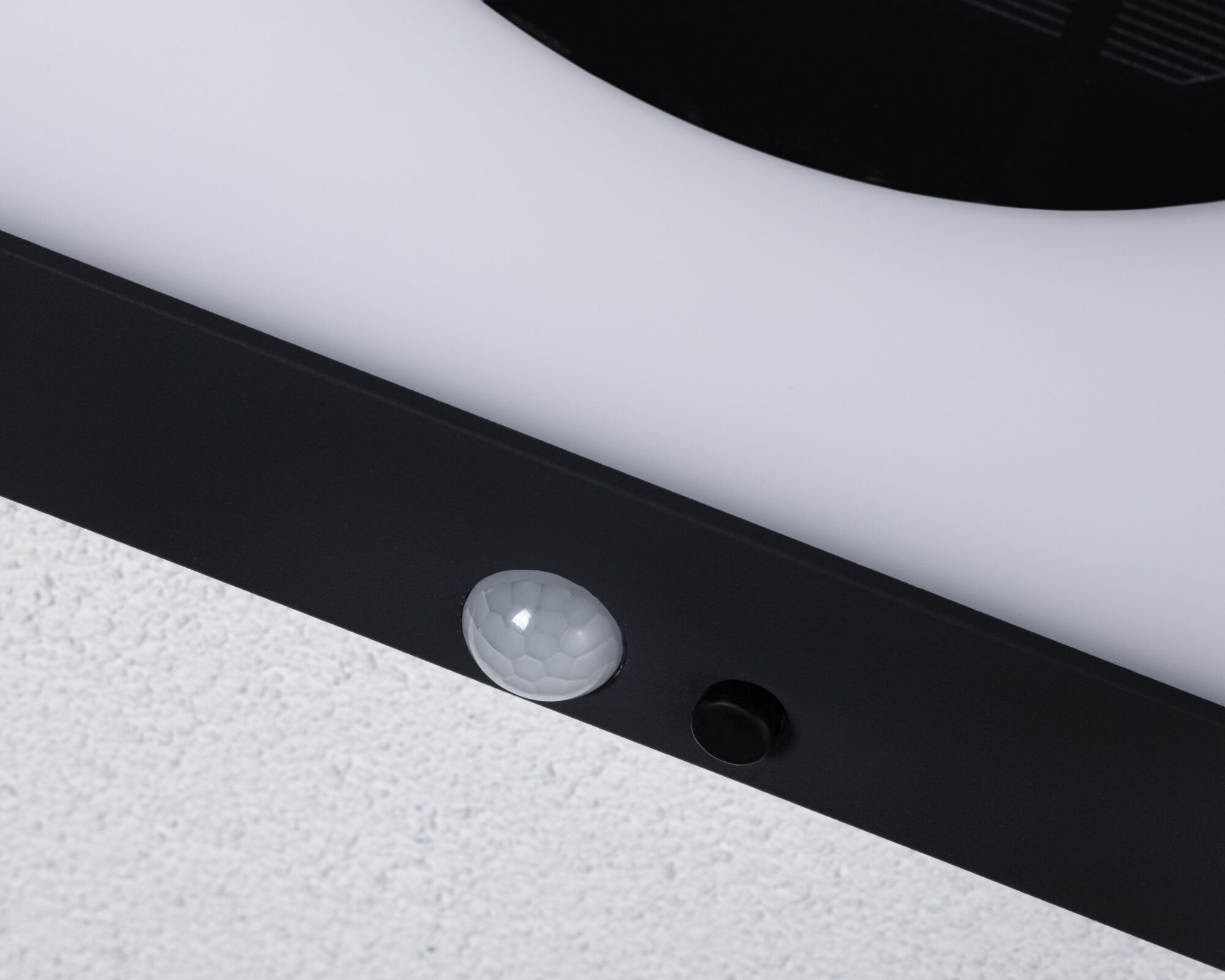 Close-up of black LED light frame with white motion sensor on white wall