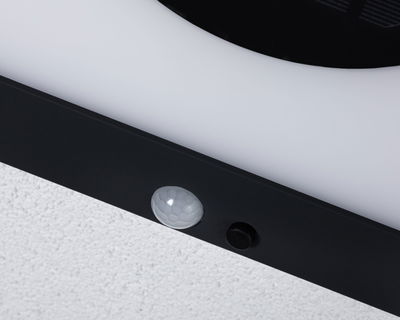 Close-up van zwart LED-lichtframe met witte bewegingssensor op witte muur