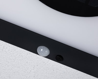 Gros plan sur cadre de lampe LED noir avec détecteur de mouvement blanc sur mur blanc