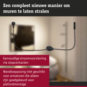 Zwart stroomkabel met stekker en schakelaar aan beige muur voor wandverlichting