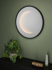 Applique murale LED ronde avec cadre noir et lumière blanc chaud dans pièce moderne avec plante.