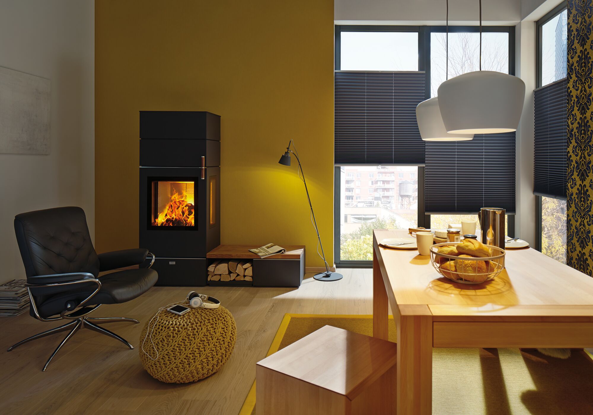 Moderne woonkamer met zwarte open haard, gele muur, houten tafel, hanglampen en broodmand