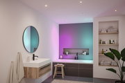 Modern bathroom with wooden vanity, round mirror, and bathtub featuring colorful LED lighting