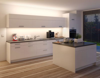 Moderne weiße Kücheninsel mit grauer Arbeitsplatte und LED-Unterbauleuchten für helle Küchenbeleuchtung