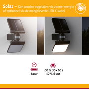Zwarte solar buitenlamp met bewegingssensor aan witte muur, dag- en nachtzicht