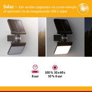 Zwarte solar buitenlamp met bewegingssensor aan witte muur, dag- en nachtzicht