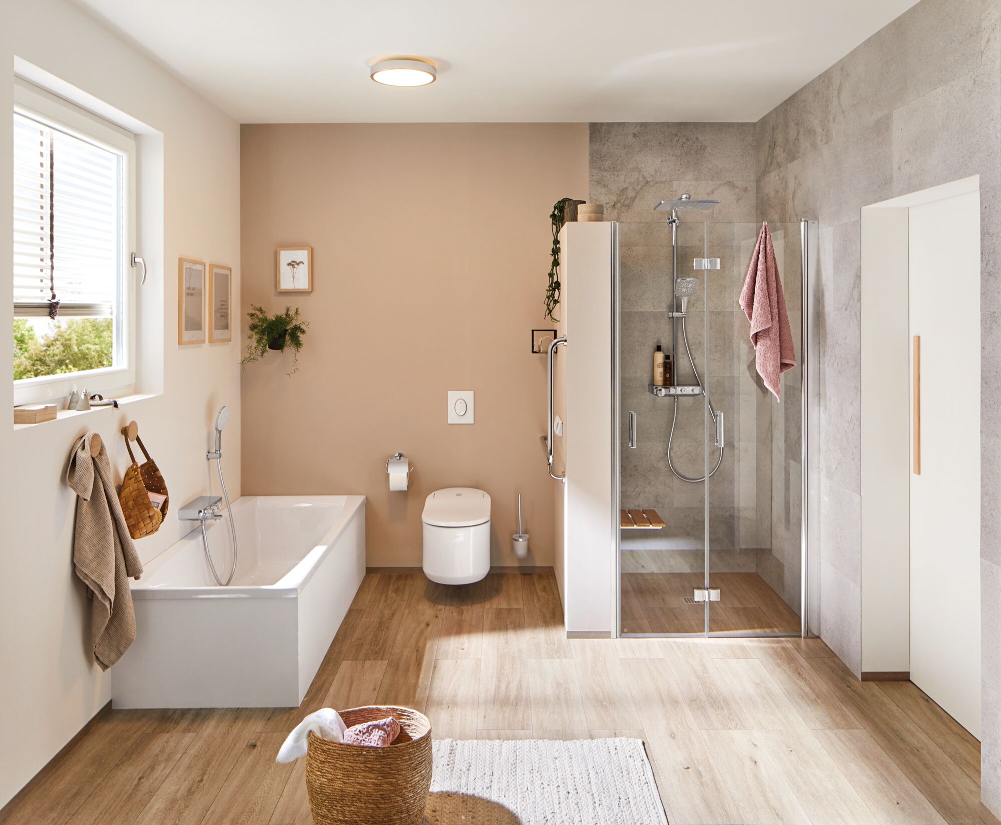 Modernes Badezimmer mit weißer Badewanne, beigem Wandton und Glasdusche mit Holzbank und Handtuch