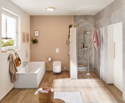 Modernes Badezimmer mit weißer Badewanne, beigem Wandton und Glasdusche mit Holzbank und Handtuch