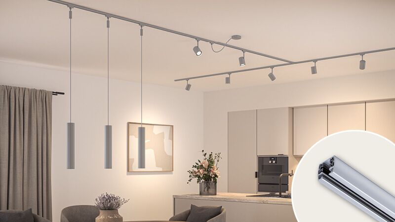 Rail d'éclairage URail chromé avec plusieurs spots dans un salon moderne avec cuisine et coin repas