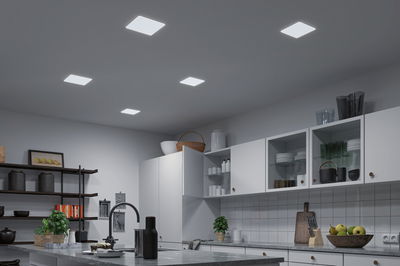 Modern kitchen with white cabinets and five square LED ceiling lights providing bright room lighting.