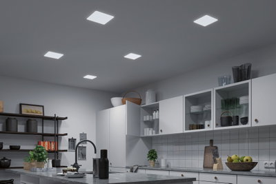 Cuisine moderne avec armoires blanches et cinq plafonniers LED carrés pour un éclairage lumineux.