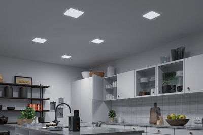 Modern kitchen with white cabinets and five square LED ceiling lights providing bright room lighting.