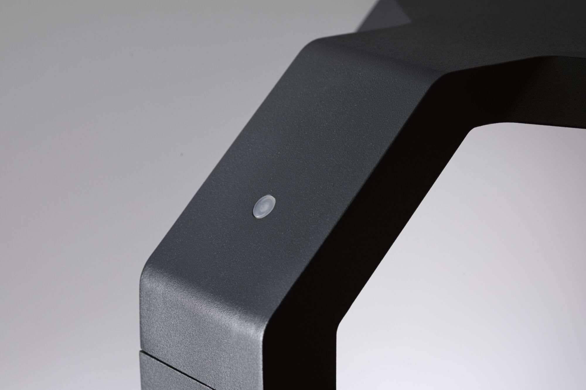 Nahaufnahme eines mattschwarzen Metallrahmens mit kleinem Sensor für moderne LED-Beleuchtung.