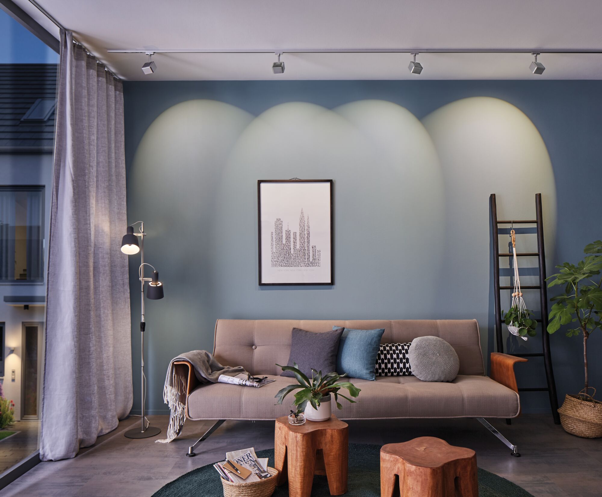 Modernes Wohnzimmer mit grauem Sofa, blauen Wandstrahlern und Holz-Hockern für gemütliche Beleuchtung.