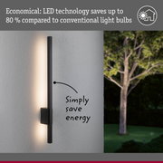 Black metal LED wall light with energy-saving illumination on grey outdoor wall for garden lighting