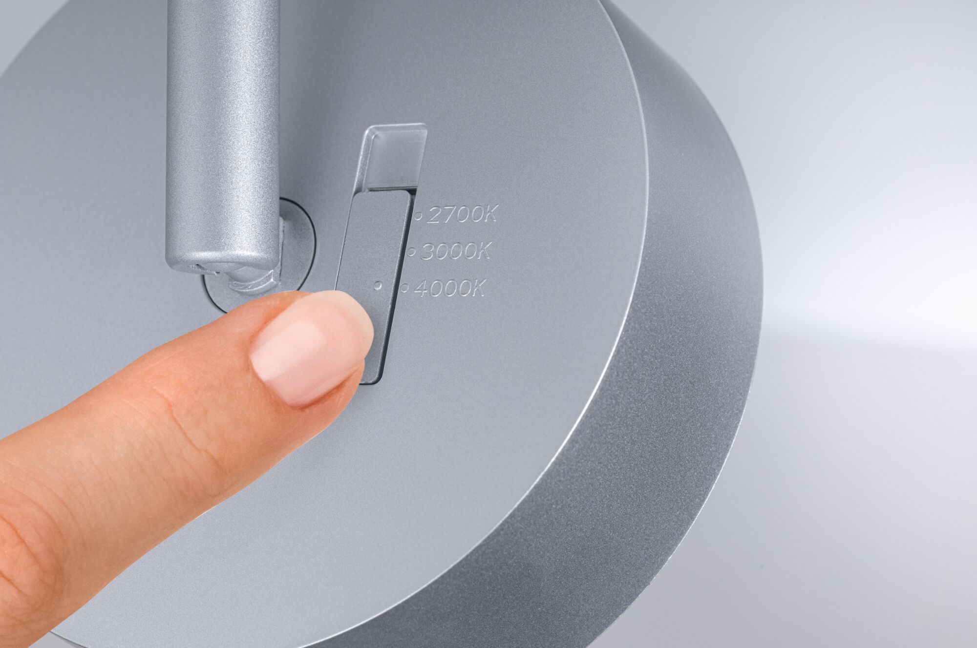Finger stellt silbernen LED-Leuchten-Drehschalter mit Farbtemperaturen 2700K, 3000K, 4000K ein