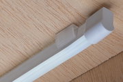 Goulotte blanche en plastique avec extrémité arrondie sur surface en bois pour gestion des câbles