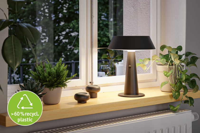 Modern table lamp made from over 60% recycled plastic on windowsill with green plants and decor.