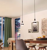 Moderne Esszimmerbeleuchtung mit zwei hängenden LED-Glühbirnen in schwarzem Design und Holzstühlen.