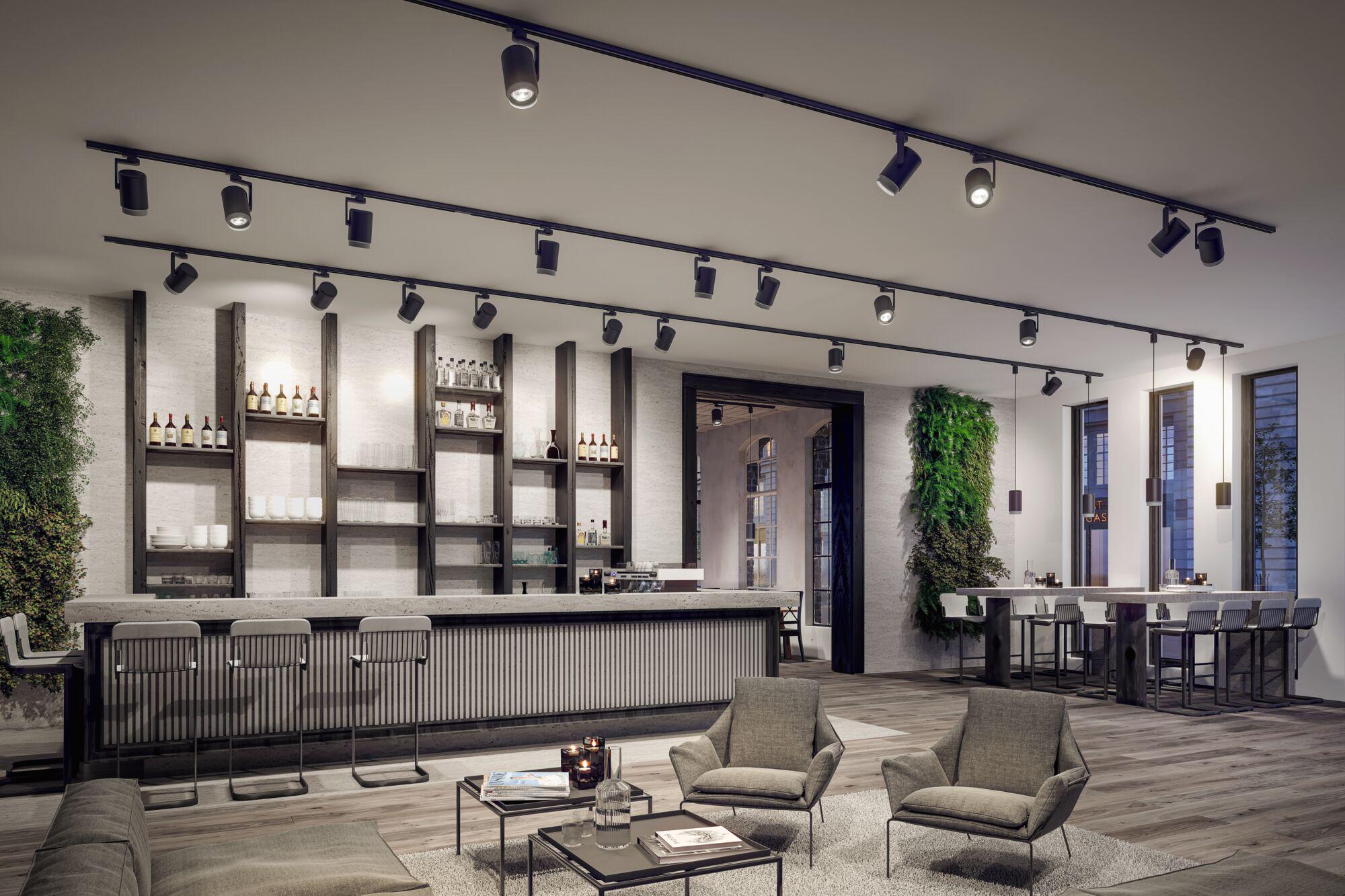 Modern black LED track spotlights on ceiling in stylish bar and lounge area with wood and concrete