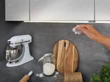 Kitchen countertop with white mixer, wooden cutting board, jar of flour and hand covered in flour