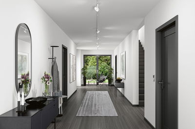 Modern hallway with white walls, grey floor, black coat rack and ceiling spotlights for living space lighting