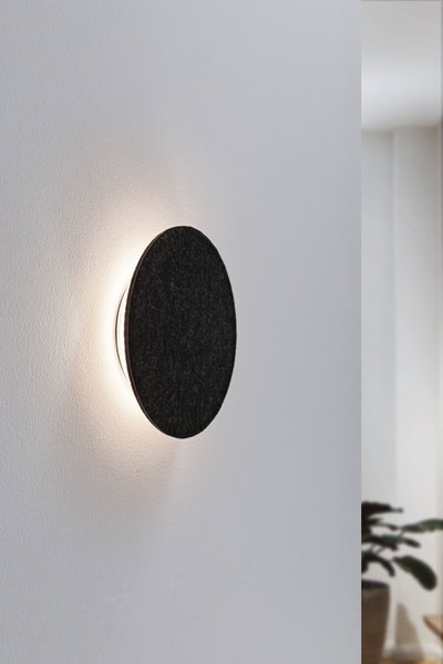 Round wall lamp with black felt cover and warm white LED light for modern living spaces.