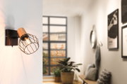 Wandlampe mit Holz und schwarzem Metallgitter, warmes Licht, modernes Wohnzimmer mit Fenster und Pflanzen.
