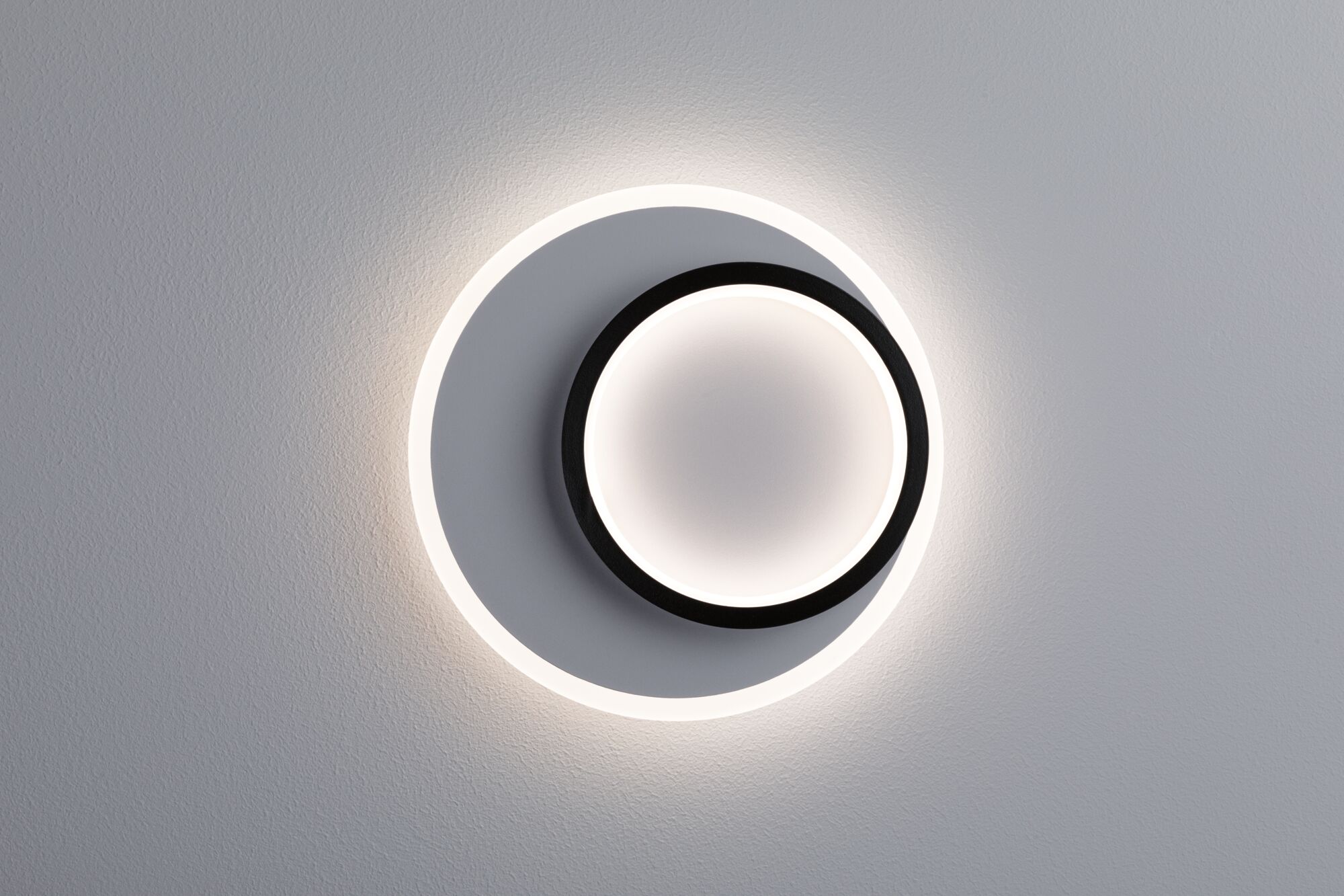 Modern round LED wall light in black and white with indirect lighting for living spaces